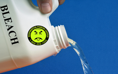 A hand pouring bleach out of a white bleach bottle with a green sticker saying Washington Poison Center 1-800-222-1222