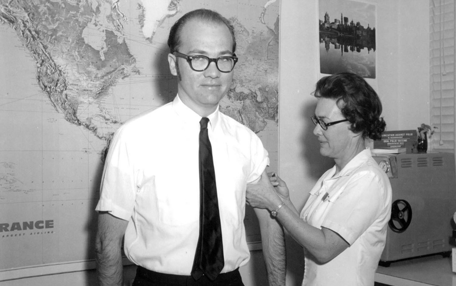 Old black and white photo from the Kittitas Public Health image archives of a nurse administering an injection to a man